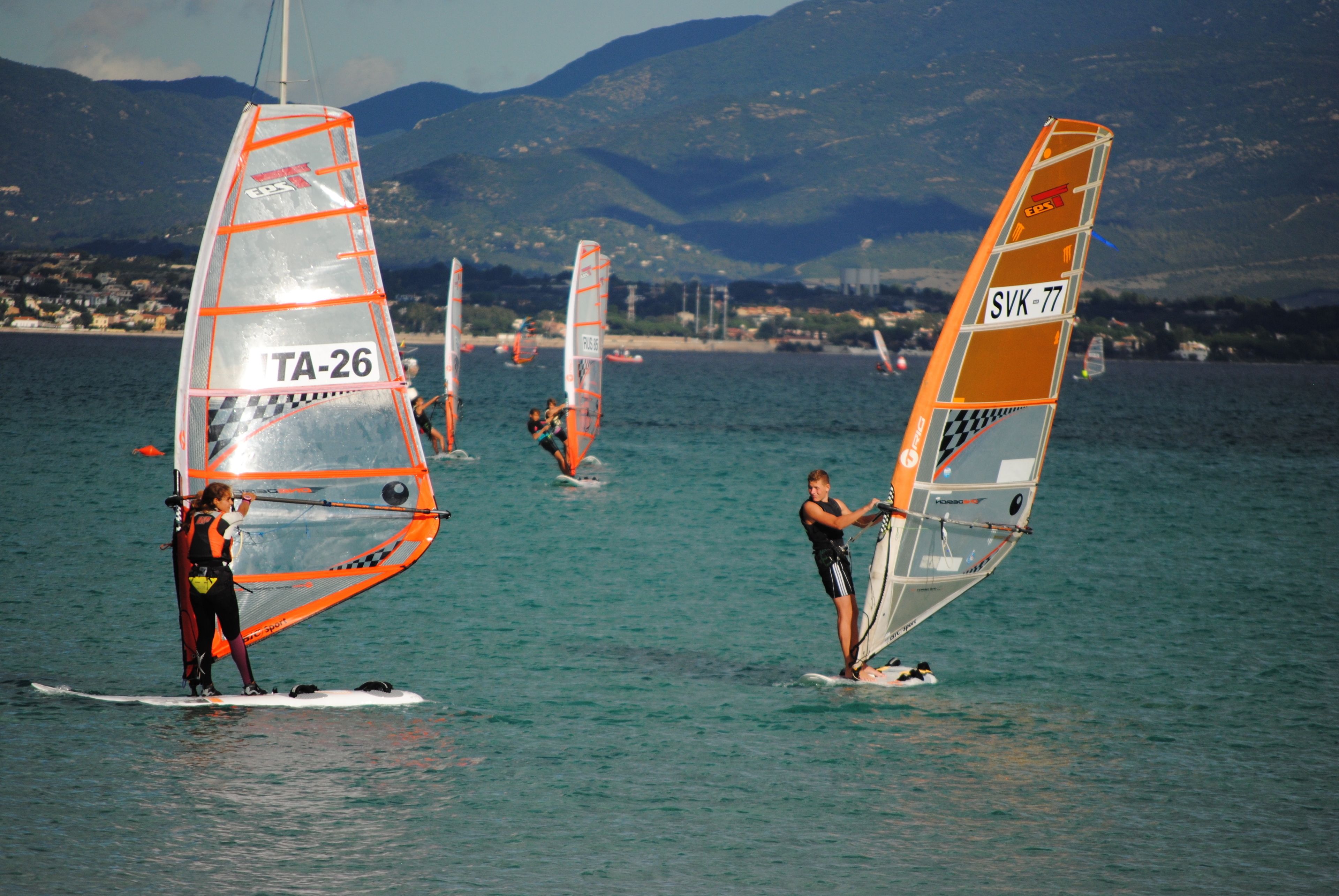 A coastal area with people windsurfing.