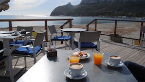 A seaside dining area with tables, chairs, and breakfast items.