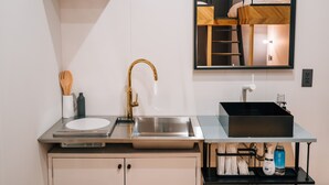 Een moderne keuken met een roestvrijstalen spoelbak, een gouden kraan en een inbouwoven.