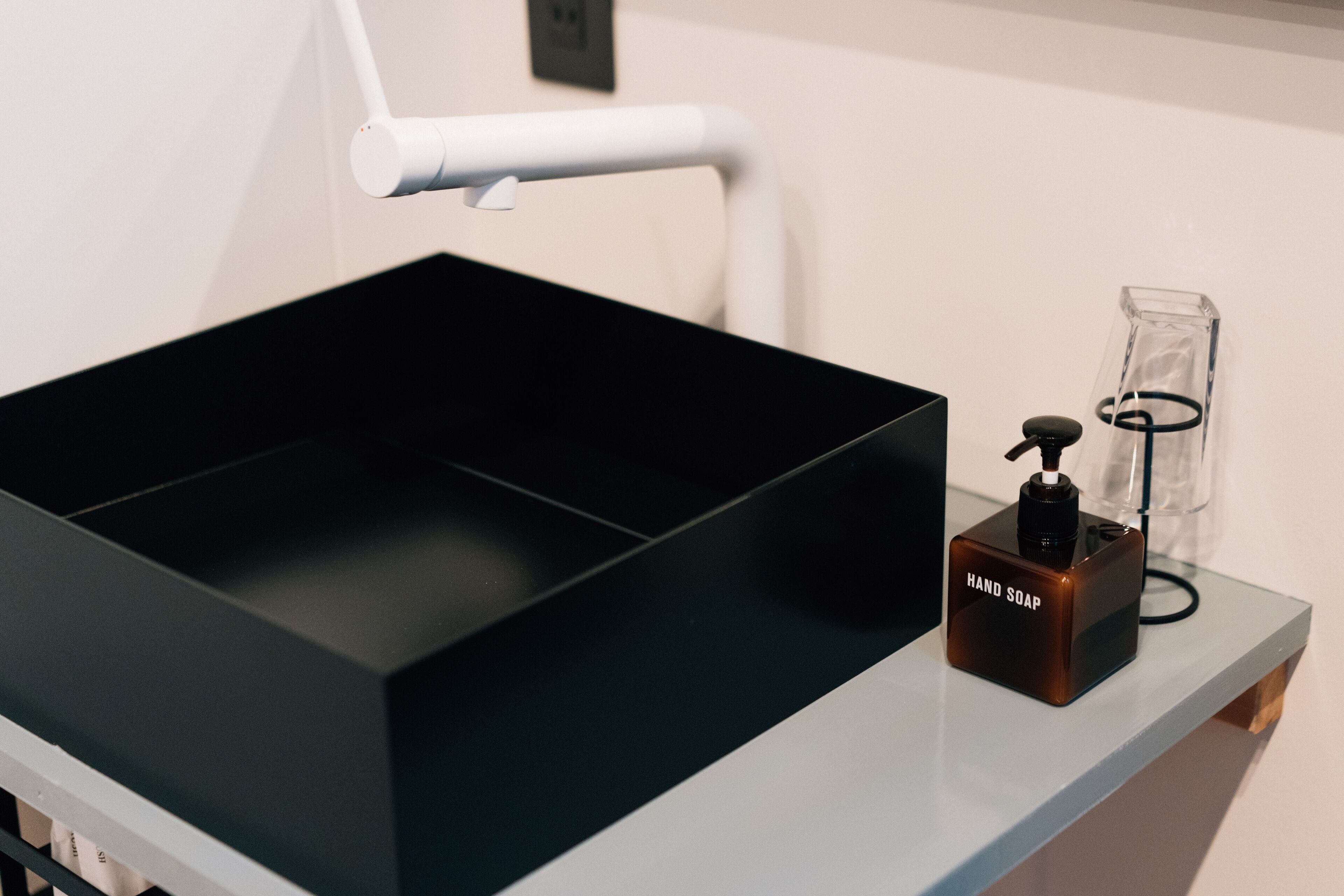 Un lavabo negro con dispensador de jabón sobre una encimera blanca.