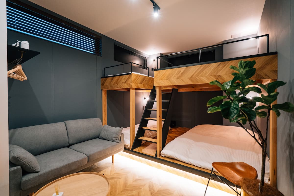 Une chambre moderne et compacte, équipée d’un lit superposé, d’un canapé et d’une petite table.