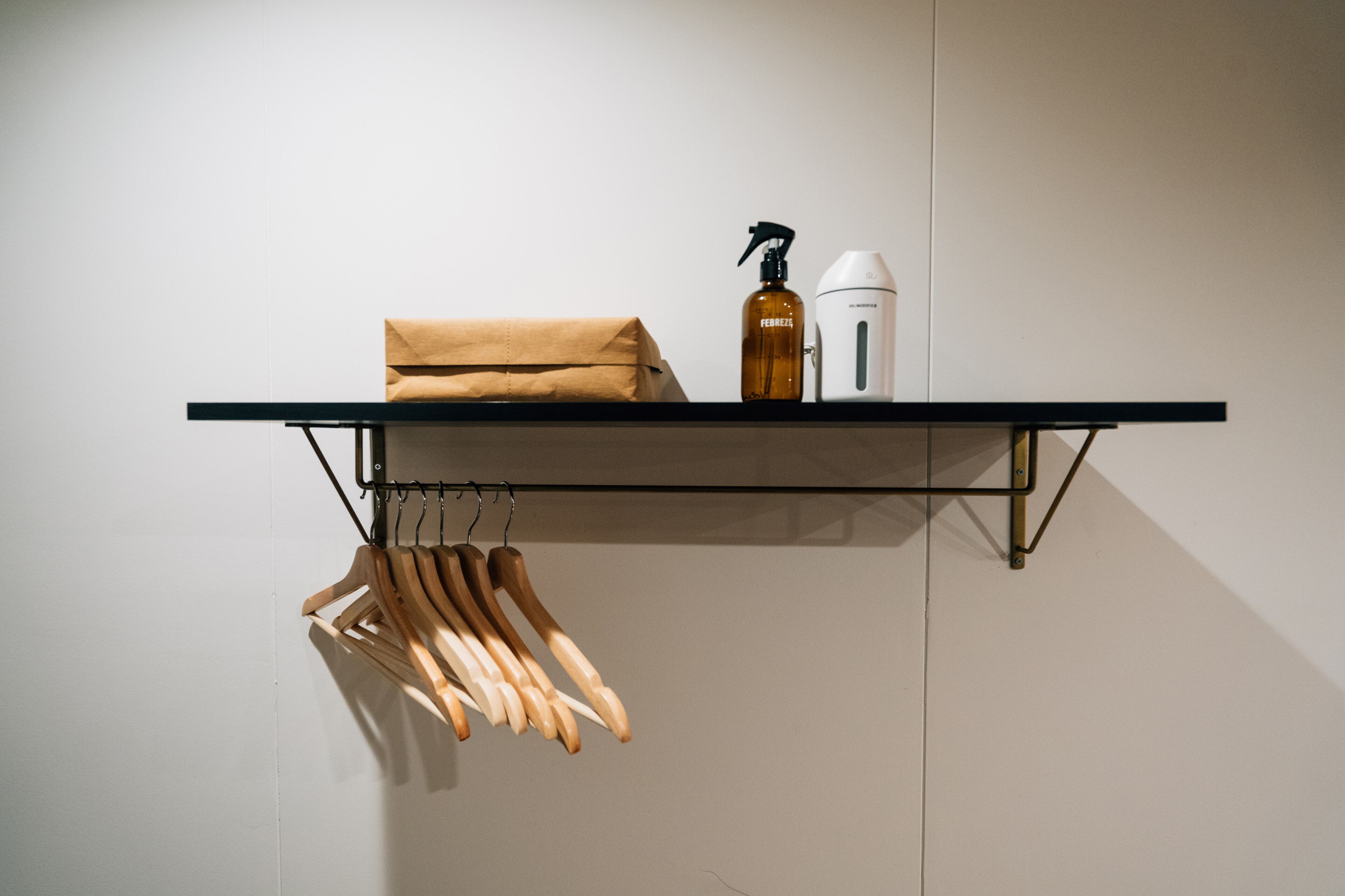 A shelf with a brown paper bag, a spray bottle, and a white device.