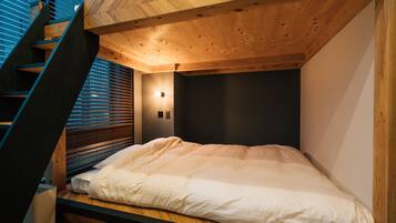 Een slaapkamer met een bed, houten plafond en een trap.