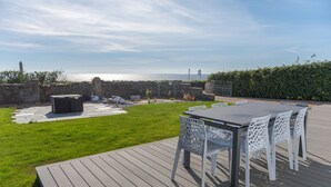 A deck with a table and chairs, a stone wall, and a view of the sea. - Le Clos de la Pointe Saint-Mathieu, Breton villa **** 180 ° sea view 2-13 pax (Plougonvelin)