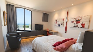 A modern bedroom with a large bed, a desk, and a TV. There is a window with a view of the outdoors. - Le Clos de la Pointe Saint-Mathieu, Breton villa **** 180 ° sea view 2-13 pax (Plougonvelin)