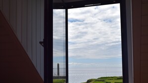 A room with a large window offering a view of a lighthouse and the sea. - Le Clos de la Pointe Saint-Mathieu, Breton villa **** 180 ° sea view 2-13 pax (Plougonvelin)