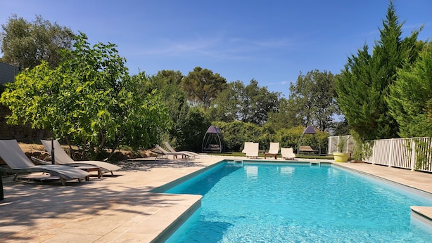 Piscina retangular com água azul cristalina, rodeada por espreguiçadeiras e um cercado branco.