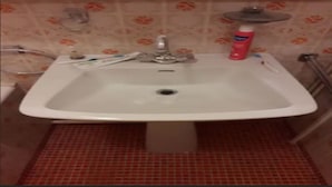 Ein Badezimmer mit einem weißen Waschbecken, einem Spiegel und einem roten Kachelboden.
