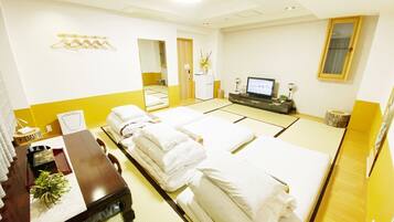 A hotel room with two beds, a desk, a TV, and a mirror.