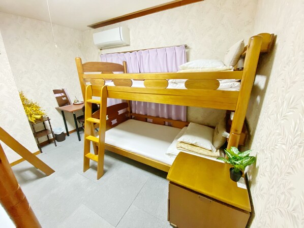 A bunk bed room with a desk, chair, and a small plant.