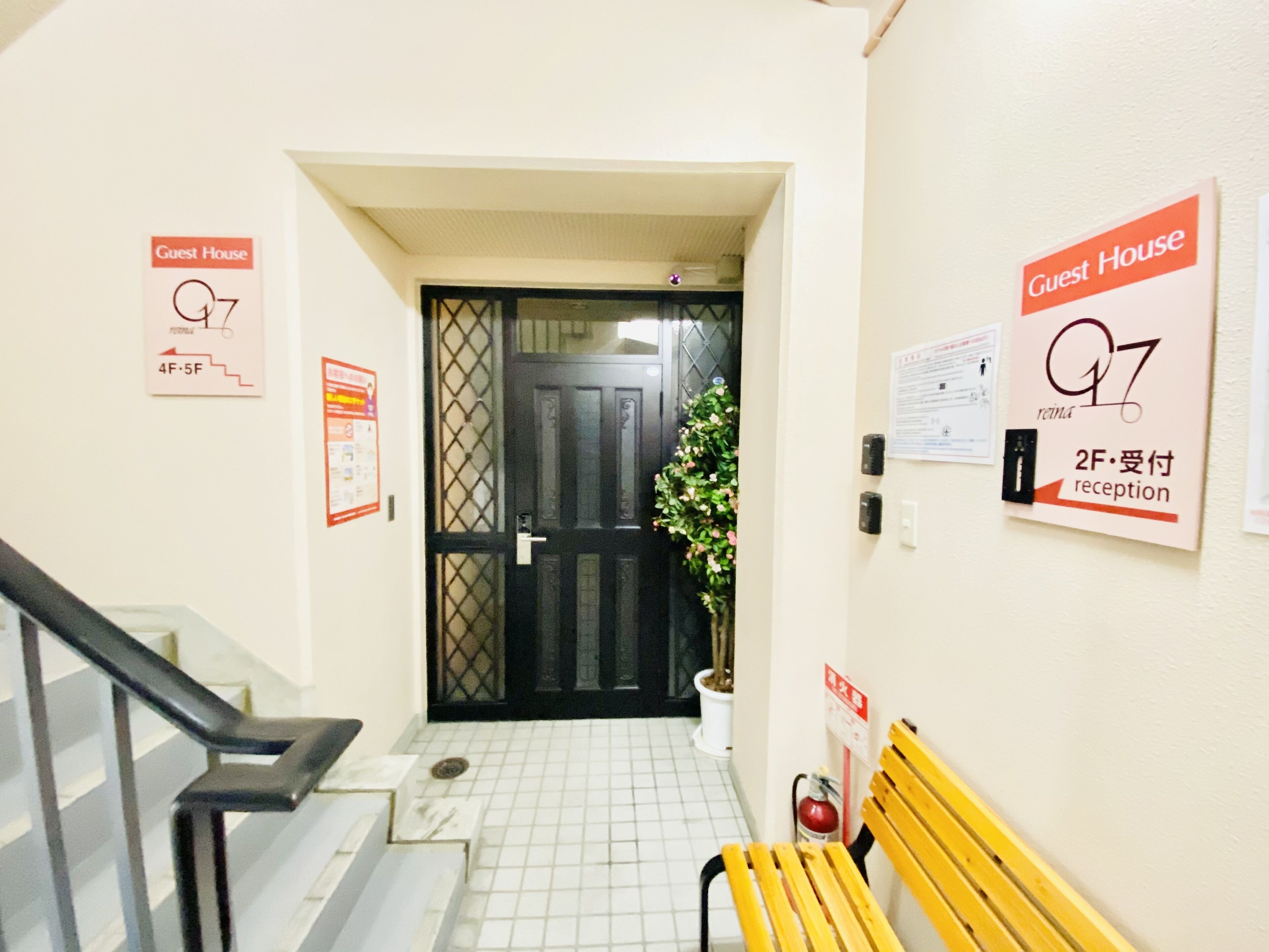 A hallway with a staircase, a bench, and signs indicating a guest house.