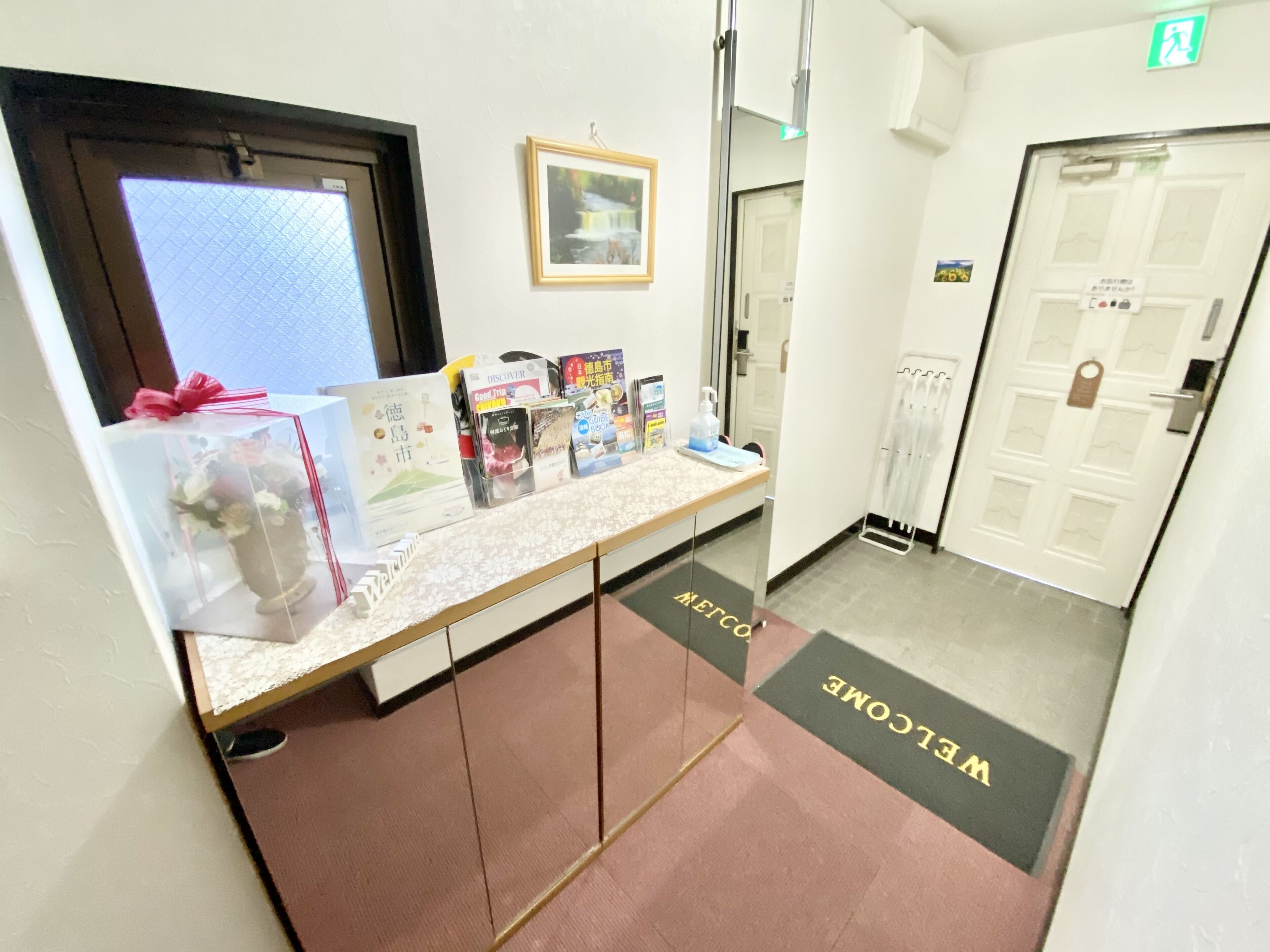 A reception desk with a welcome mat, informational brochures, and a framed picture on the wall.