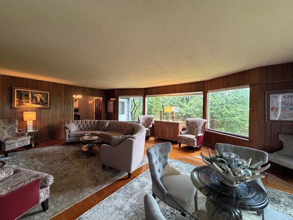 A cozy living room with a sectional sofa, armchairs, a glass coffee table, and a fireplace.