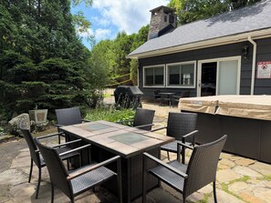 An outdoor patio with a table and chairs, a barbecue grill, and a covered area.