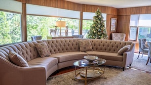 A cozy living room with a large sectional sofa, a glass coffee table, and a Christmas tree. -  Walk to Village View Lake Placid Hot Tub, Fire Pit, Volleyball, kids playground (Lake Placid)