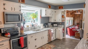A modern kitchen with white cabinets, stainless steel appliances, and a red towel hanging on the oven. -  Walk to Village View Lake Placid Hot Tub, Fire Pit, Volleyball, kids playground (Lake Placid)