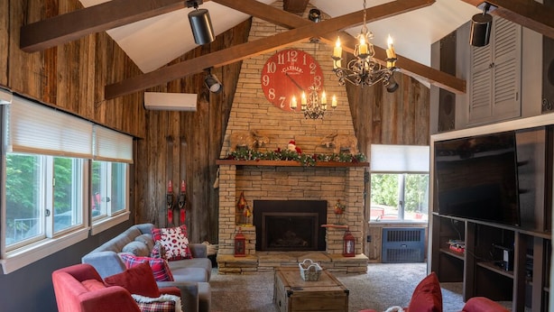 A cozy living room with a fireplace, red sofas, and a television. -  Walk to Village View Lake Placid Hot Tub, Fire Pit, Volleyball, kids playground (Lake Placid)