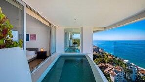 A modern balcony with a pool, overlooking a coastal cityscape.