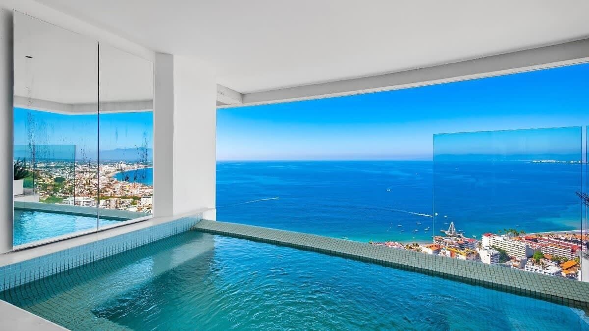 A modern infinity pool with a clear view of the ocean and distant cityscape.
