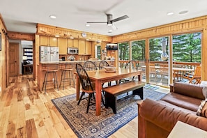 A spacious kitchen with wooden cabinets, a dining area with a large table and chairs, and a cozy seating area with a brown leather couch.