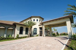 A large building with a covered entrance, palm trees, and a paved driveway.