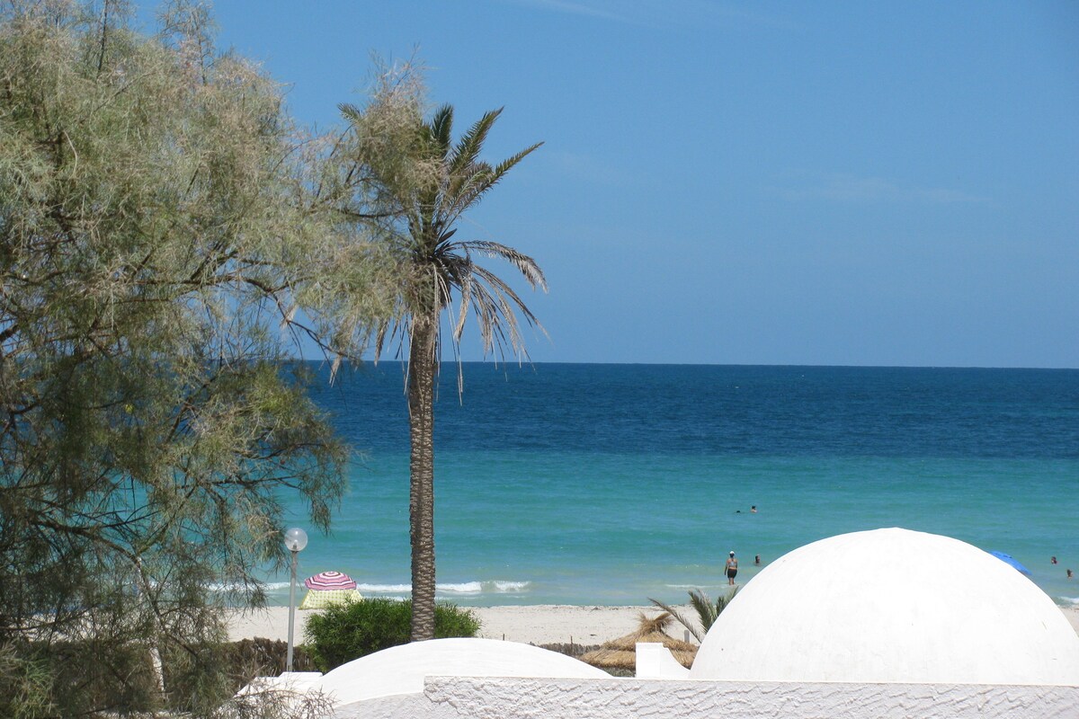 A beach with palm trees, a clear sky, and the ocean.