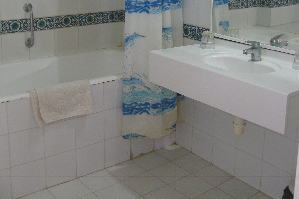 A bathroom with a bathtub, a sink, and a shower curtain with a dolphin design.
