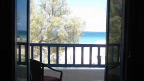 A balcony with a chair and table, overlooking a beach and trees. - Dar Salem (Mezraia)
