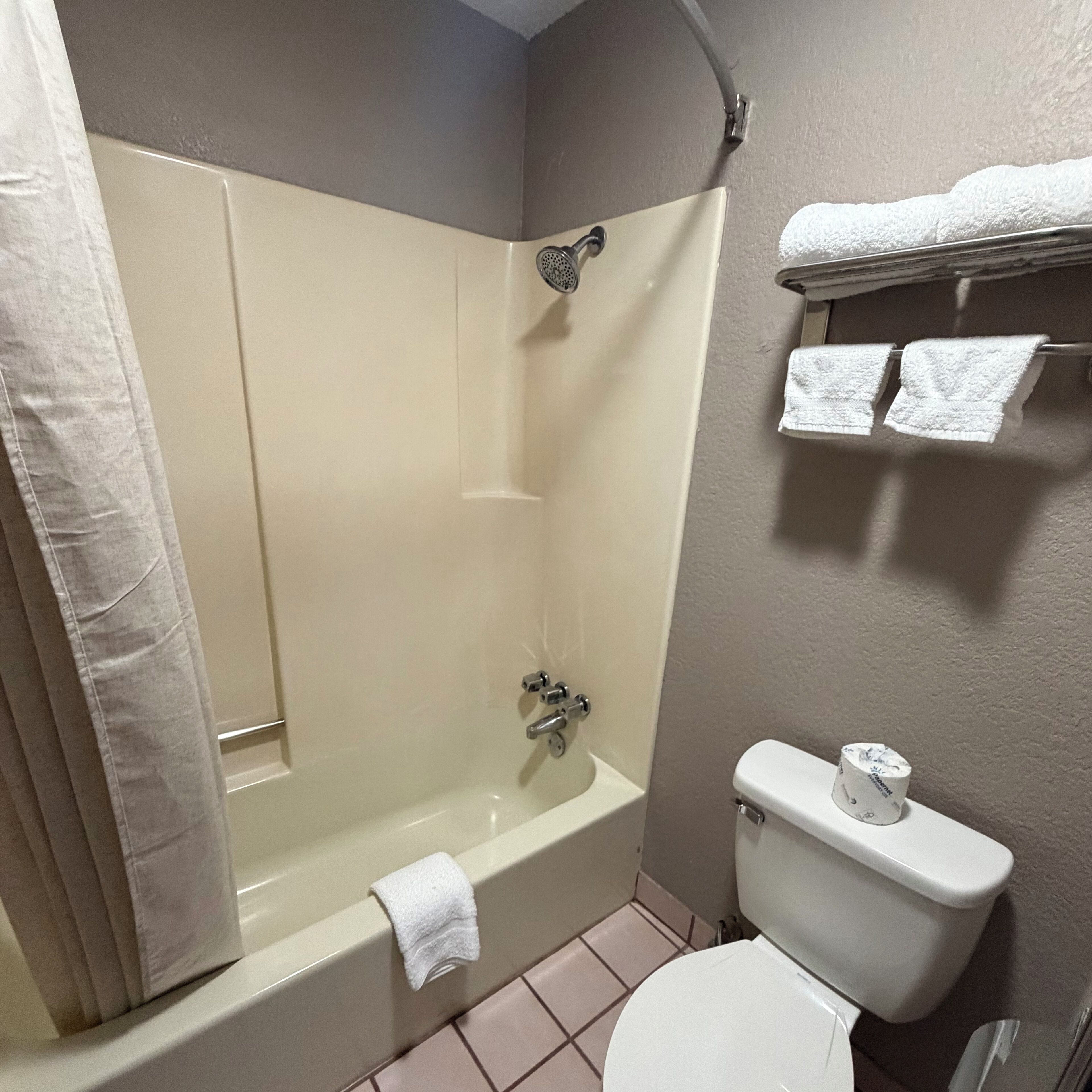 A bathroom with a bathtub, toilet, and towel rack.