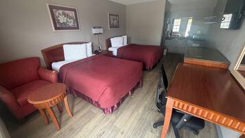 Una habitación de hotel con dos camas, un escritorio, una silla y una pequeña mesa.