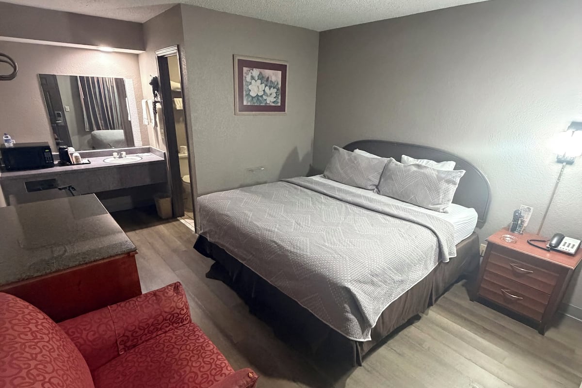 A bedroom with a bed, a desk, a chair, and a nightstand.
