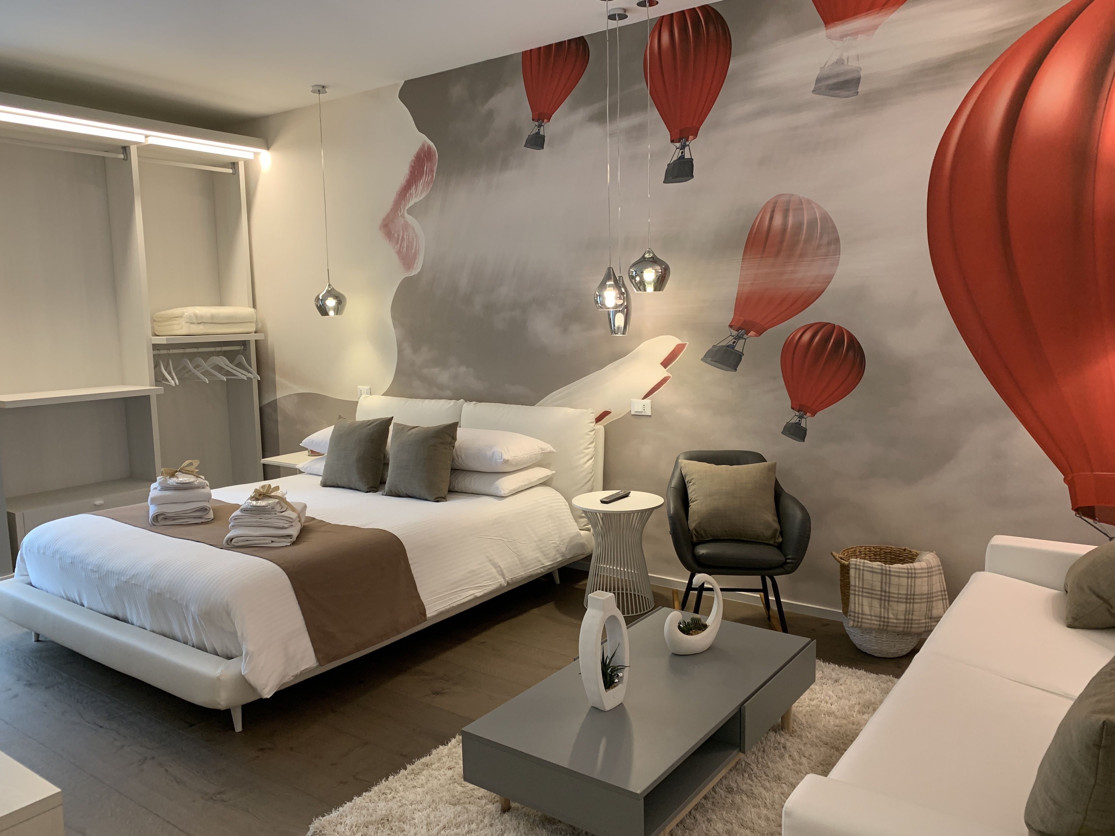 A modern bedroom with a large bed, bedside tables, a chair, and a sofa.
