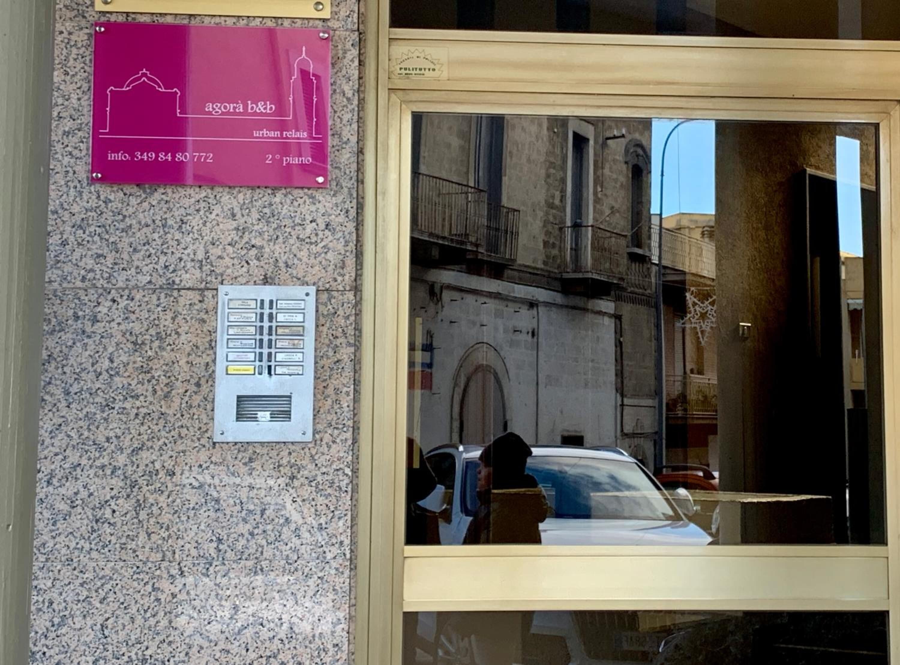 Fachada de un edificio con un letrero que indica 'agora b&b' y 'urban relax', junto con un número de contacto.