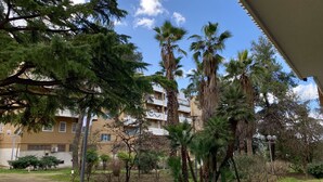 A residential building with multiple balconies, surrounded by various trees including palm trees. - Agorà B&B Urban Relais (Canosa di Puglia)