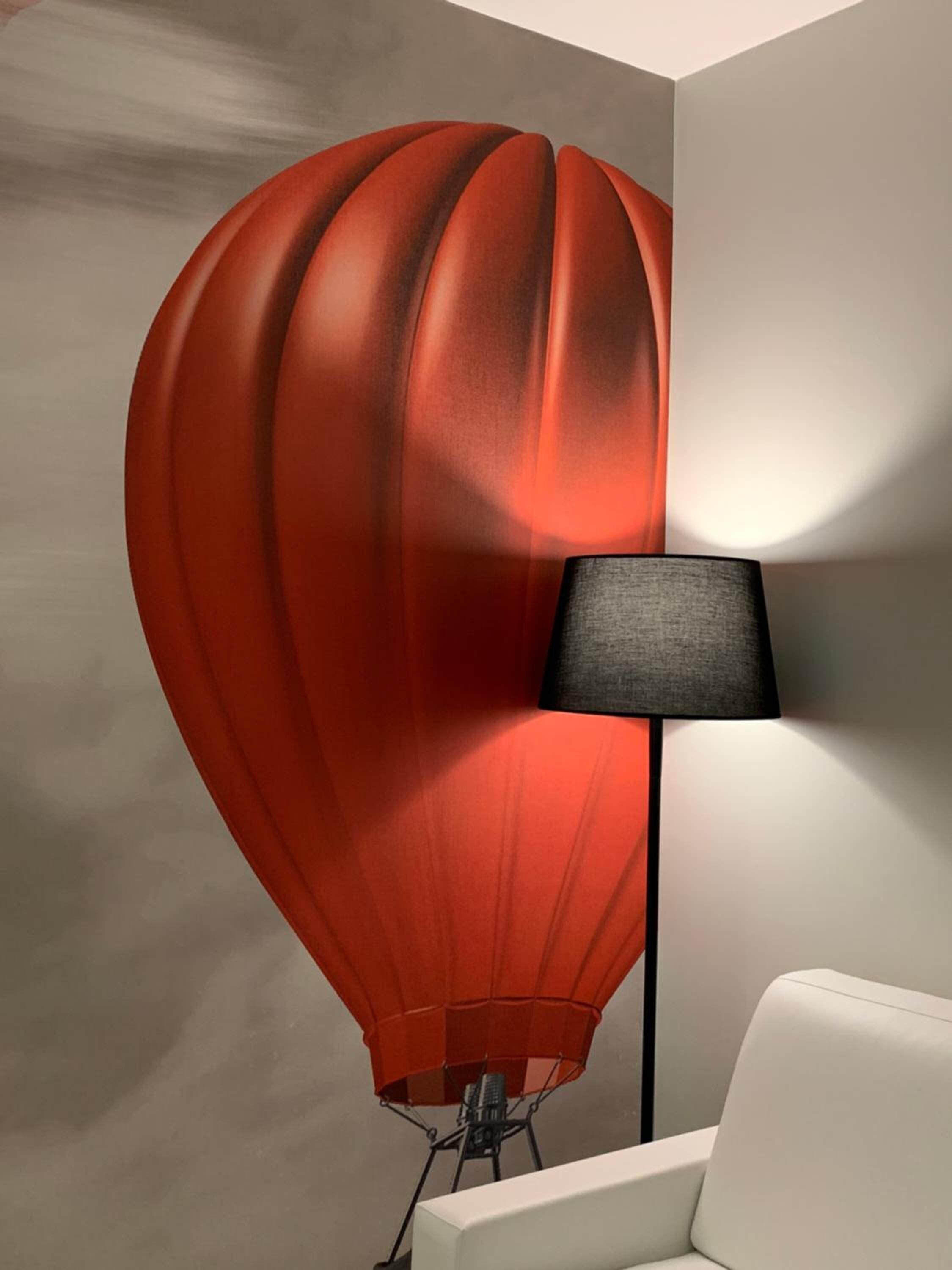 A room with a modern lamp and a unique red balloon-shaped wall decoration.