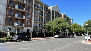 A multi-story residential building with balconies, a parking area, and a clear blue sky. - ADELAIDE CENTRAL APARTMENT - 3BR, 2BATH & CARPARK (Adelaide)