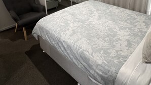 A bedroom with a bed, a chair, a large mirror, and a window with curtains. - ADELAIDE CENTRAL APARTMENT - 3BR, 2BATH & CARPARK (Adelaide)