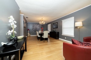 A dining area with a table and chairs, a chandelier, and a red sofa.
