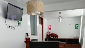 Una sala de estar moderna con un sofá, un televisor montado en la pared y un mostrador de recepción al fondo.
