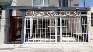 Entrada de hotel con acceso por portón y un letrero que dice "Hostal Tierra del Sol".