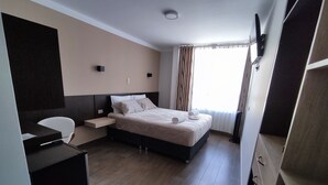 Una habitación de hotel moderna con cama, mesita de noche y escritorio con silla.