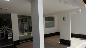 Un pasillo de hotel con paredes blancas, piso de baldosas y una puerta de cristal con un letrero que dice "Fiesta del Sol".