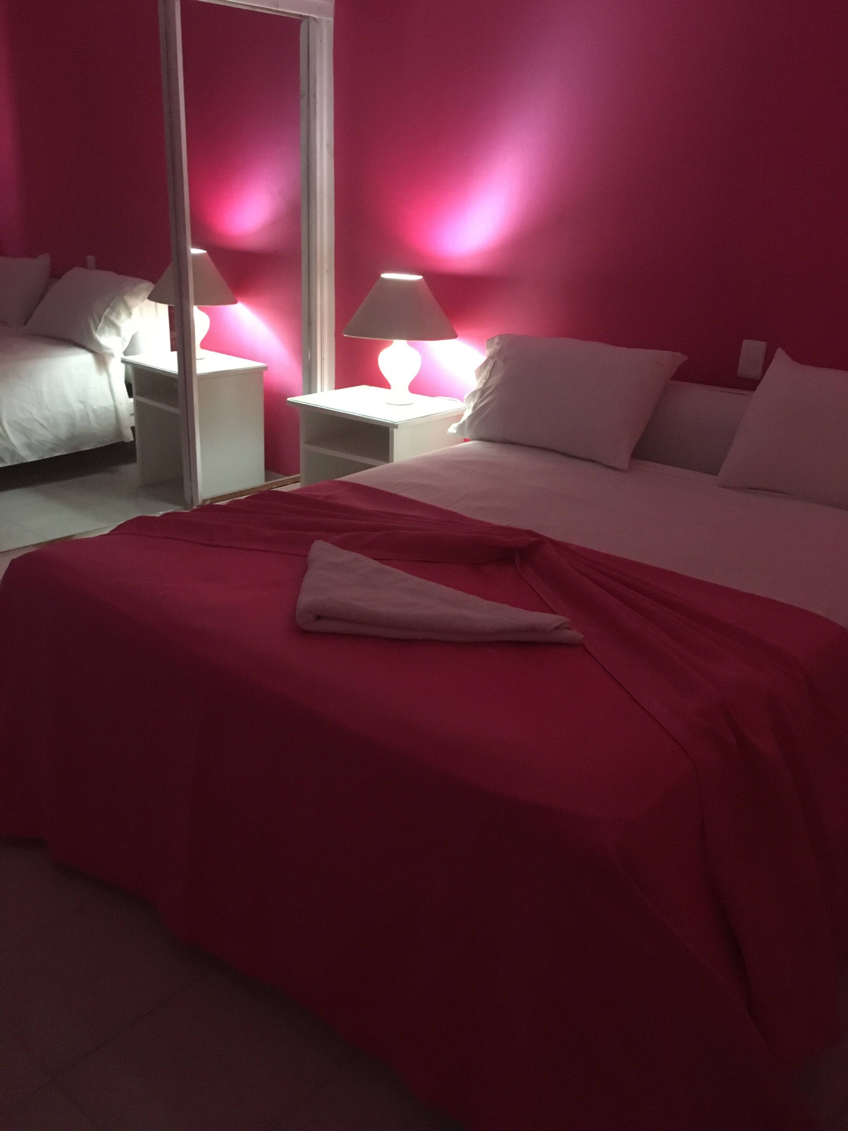 Un dormitorio con cama, mesitas de noche y un espejo.