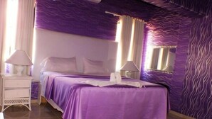 Una habitación con una cama, dos mesitas de noche y un ventanal.