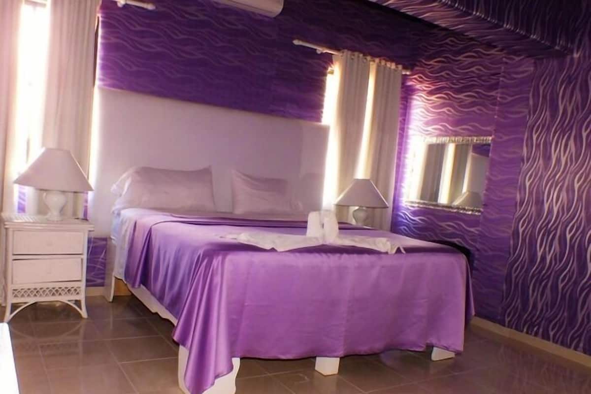 Una habitación con una cama, dos mesitas de noche y un ventanal.