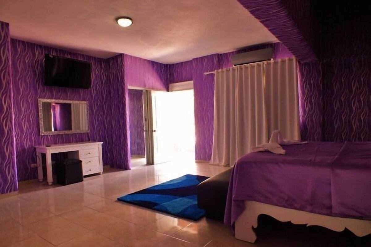 Un dormitorio con cama, tocador, televisor y puerta que da al exterior.