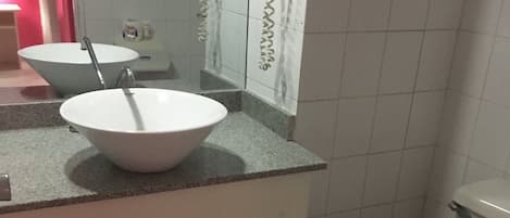 Une salle de bain avec un lavabo blanc, un miroir et des toilettes.