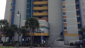 A multi-story parking garage with a modern design, featuring a mix of yellow and blue colors on the balconies. - Beautiful Direct Oceanfront 2-BR Condo on Top Floor at Broadwalk, Downtown (Myrtle Beach)