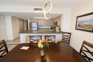 A modern kitchen with a central island, stainless steel appliances, and a dining area with a wooden table and chairs.