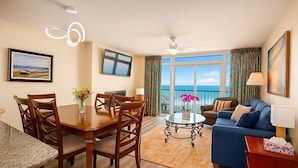 A modern hotel room with a dining area, a living room with a view of the ocean, and a balcony with curtains. - Beautiful Direct Oceanfront 2-BR Condo on Top Floor at Broadwalk, Downtown (Myrtle Beach)